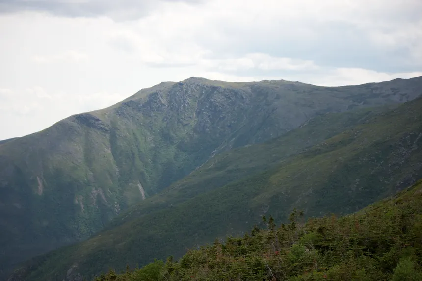 Stunning mountain view with lush green valleys under a cloudy sky.