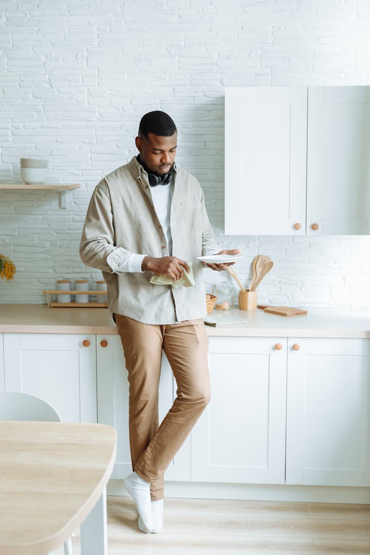 Photo Of A Man In Brown Pants Cleaning A Plate