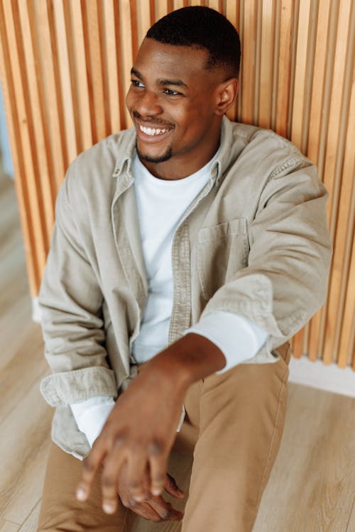 Photo of a Man in a White Shirt Sitting on the Floor while Smiling