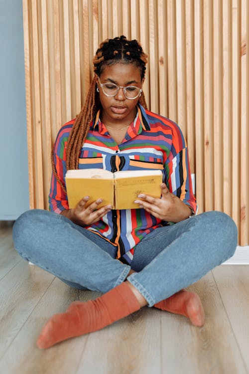 Photo of a Woman in Denim Jeans Reading a Book