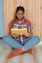 Photo of a Woman in Denim Jeans Reading a Book