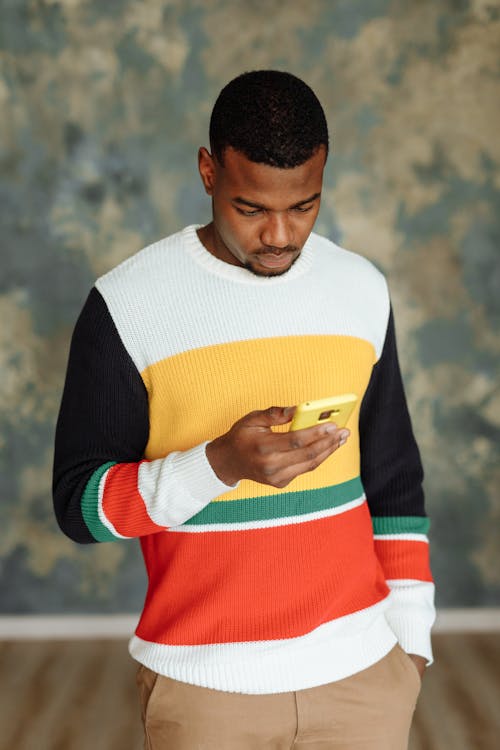 Photo of a Man in a Knitted Sweater Using His Cell Phone