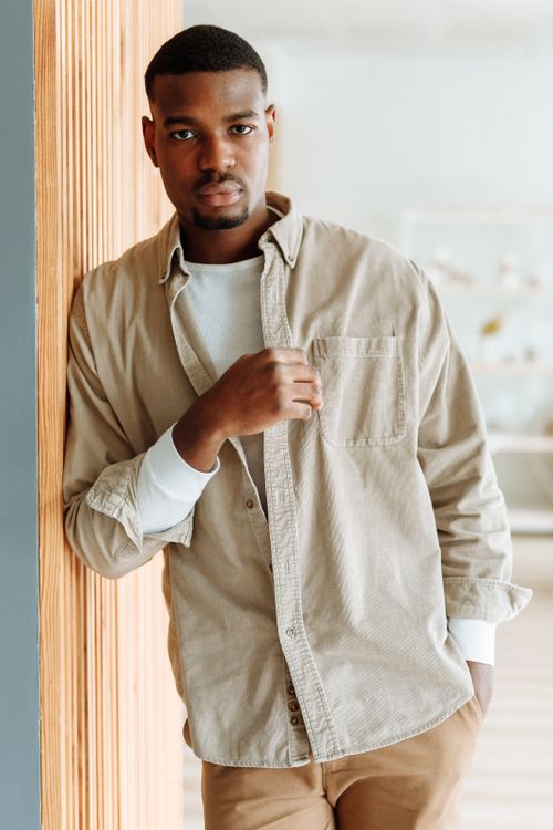 Free Fashionable man in a casual outfit leaning against a wall, exuding confidence indoors. Stock Photo