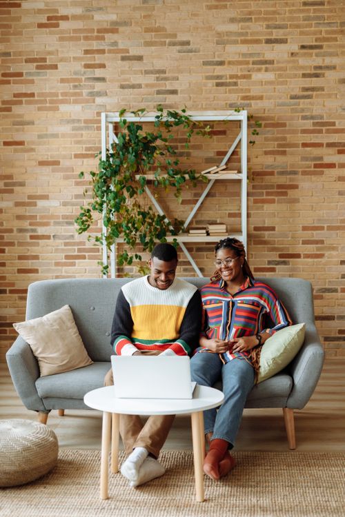 Free Two friends enjoying leisure time together on a cozy sofa, engaged with a laptop. Stock Photo