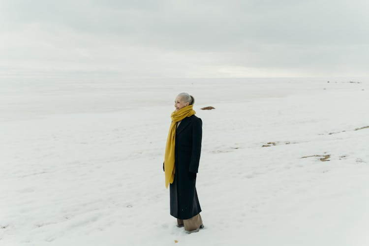 Photo Of A Woman In A Black Coat Standing On White Snow