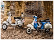 一辆经典滑板车停在德文郡的旧砖拱门下，展现出复古的城市风格