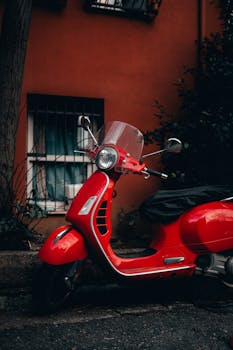 Stylish red scooter parked against an urban building backdrop, capturing a city vibe.