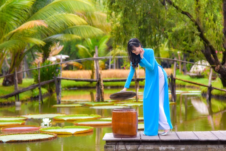 Photo Of A Woman In A Blue Dress Opening A Wooden Jar