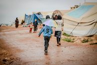 Children walk on a dirt road in a refugee camp in Idlib, Syria.