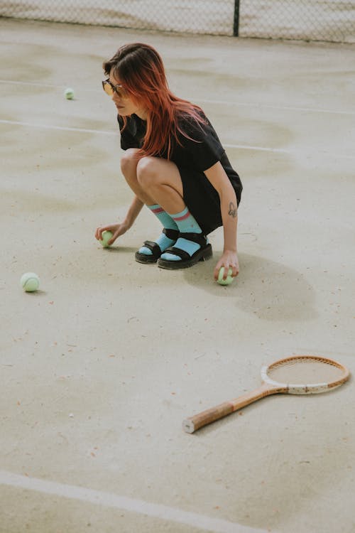 Photograph of a Woman Picking Up Tennis Balls