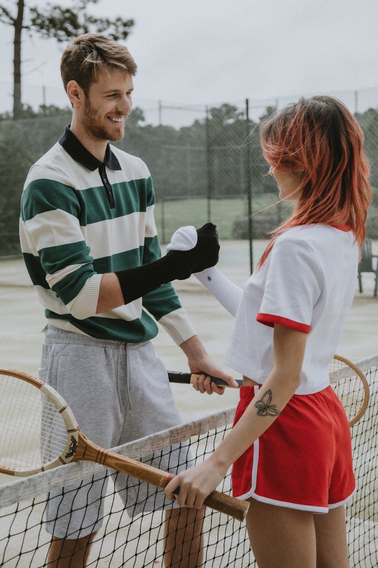 Man And Woman Holding Tennis Rackets