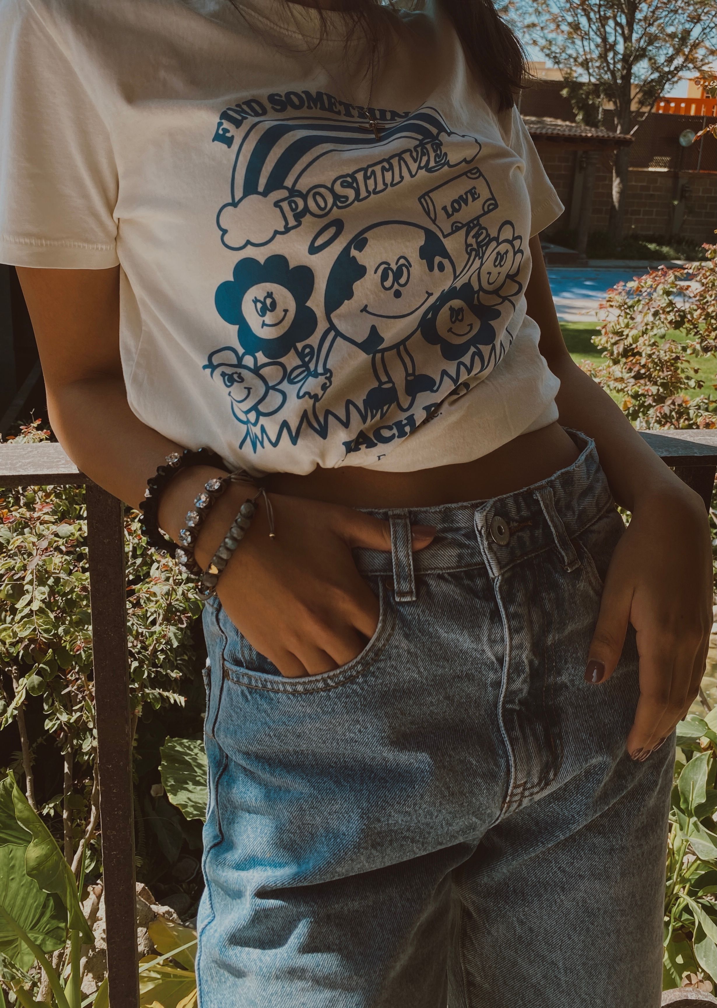 Cropped graphic T-shirt worn with high-waisted blue jeans