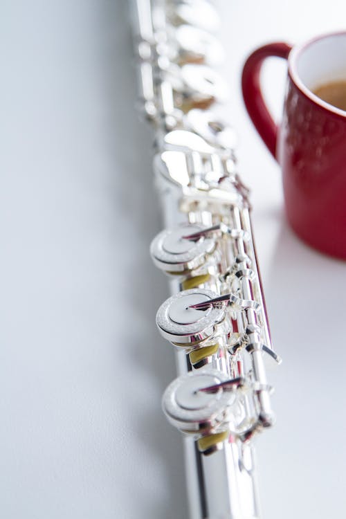 Close-Up Shot of a Silver Flute beside a Cup of Coffee