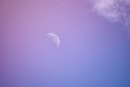 A serene view of the crescent moon against a pastel purple sky in twilight.
