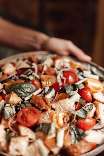 A rustic bowl of gazpachada showing chunks of soaked stale bread mixed with diced tomato, cucumber, and green pepper in a garlicky olive oil broth, topped with flaked tuna.
