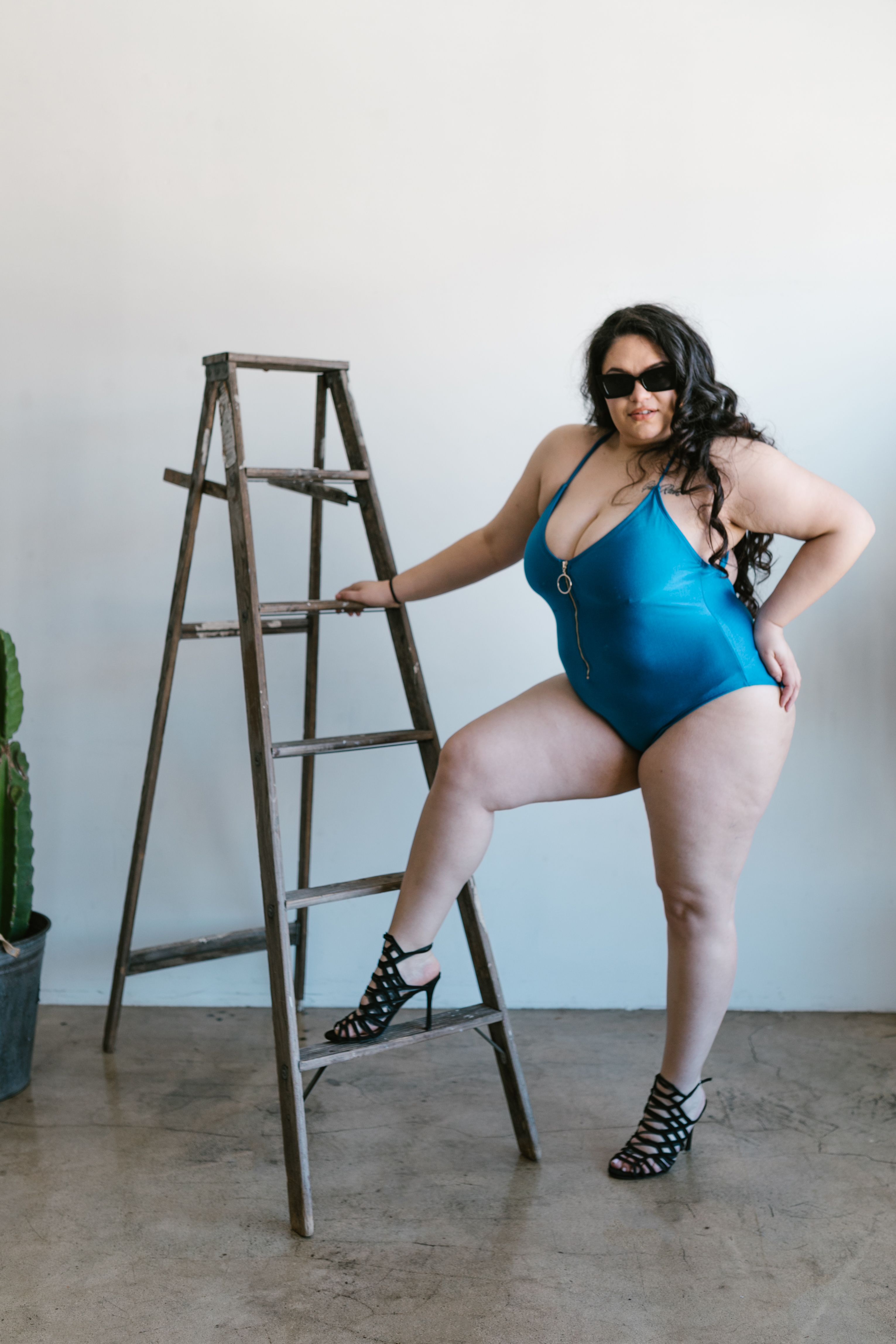 Mulher plus size empoderada em traje de banho estiloso e óculos de sol, abraçando a positividade corporal.
