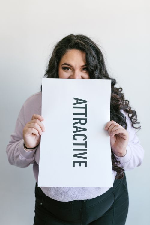 Free Young woman embraces self-love and body positivity, holding an empowerment placard. Stock Photo