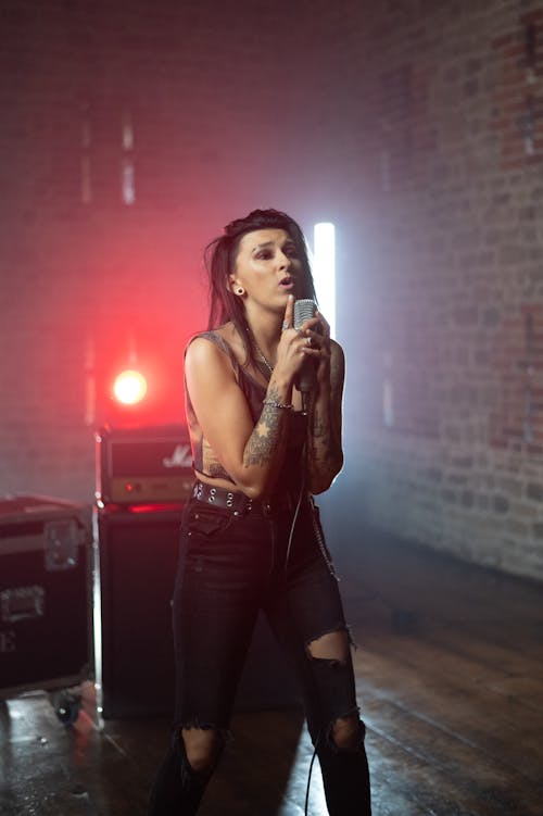 Woman in Tank Top and Black Pants Holding a Microphone