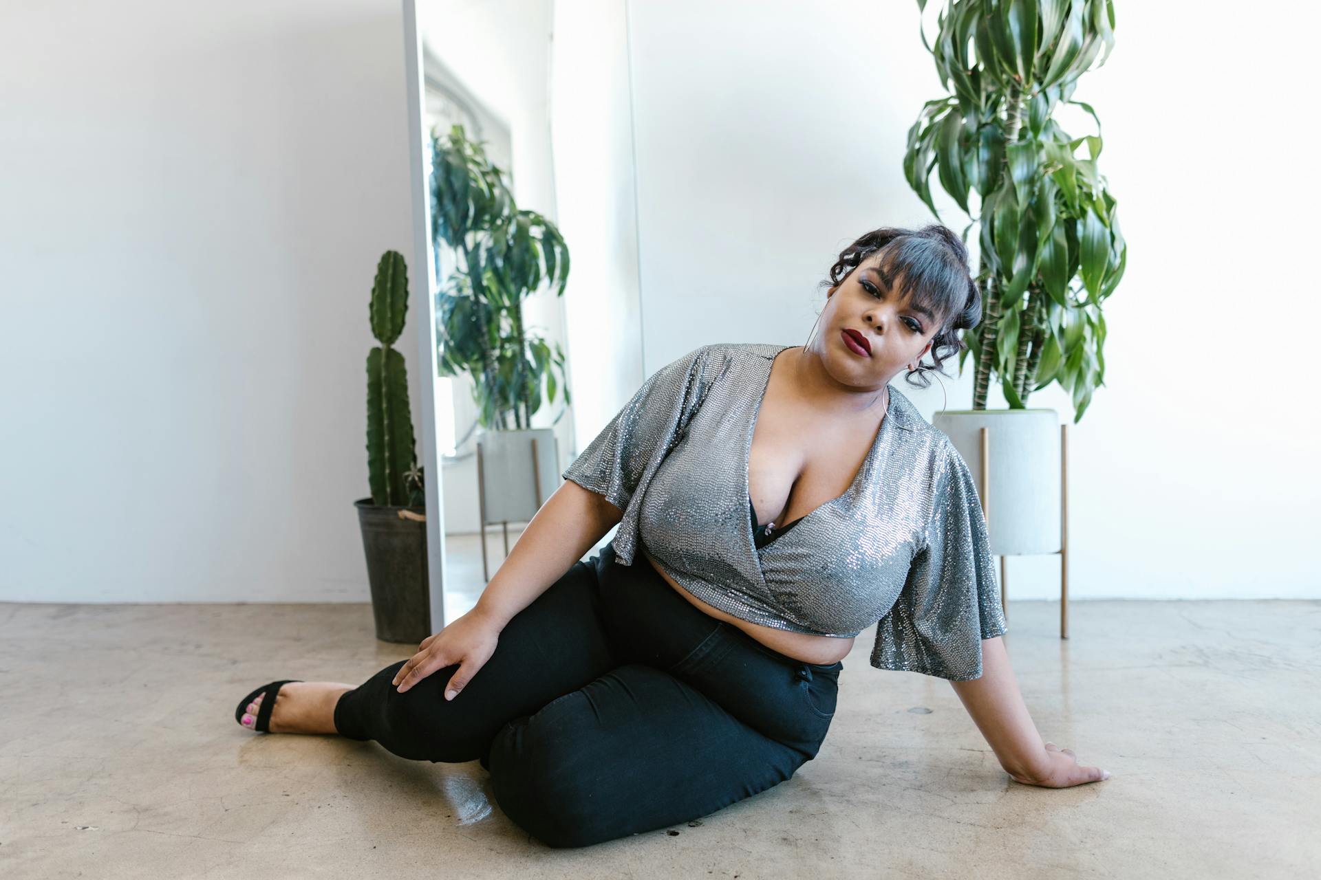 Empowered plus size model radiating confidence indoors with trendy fashion and natural decor.