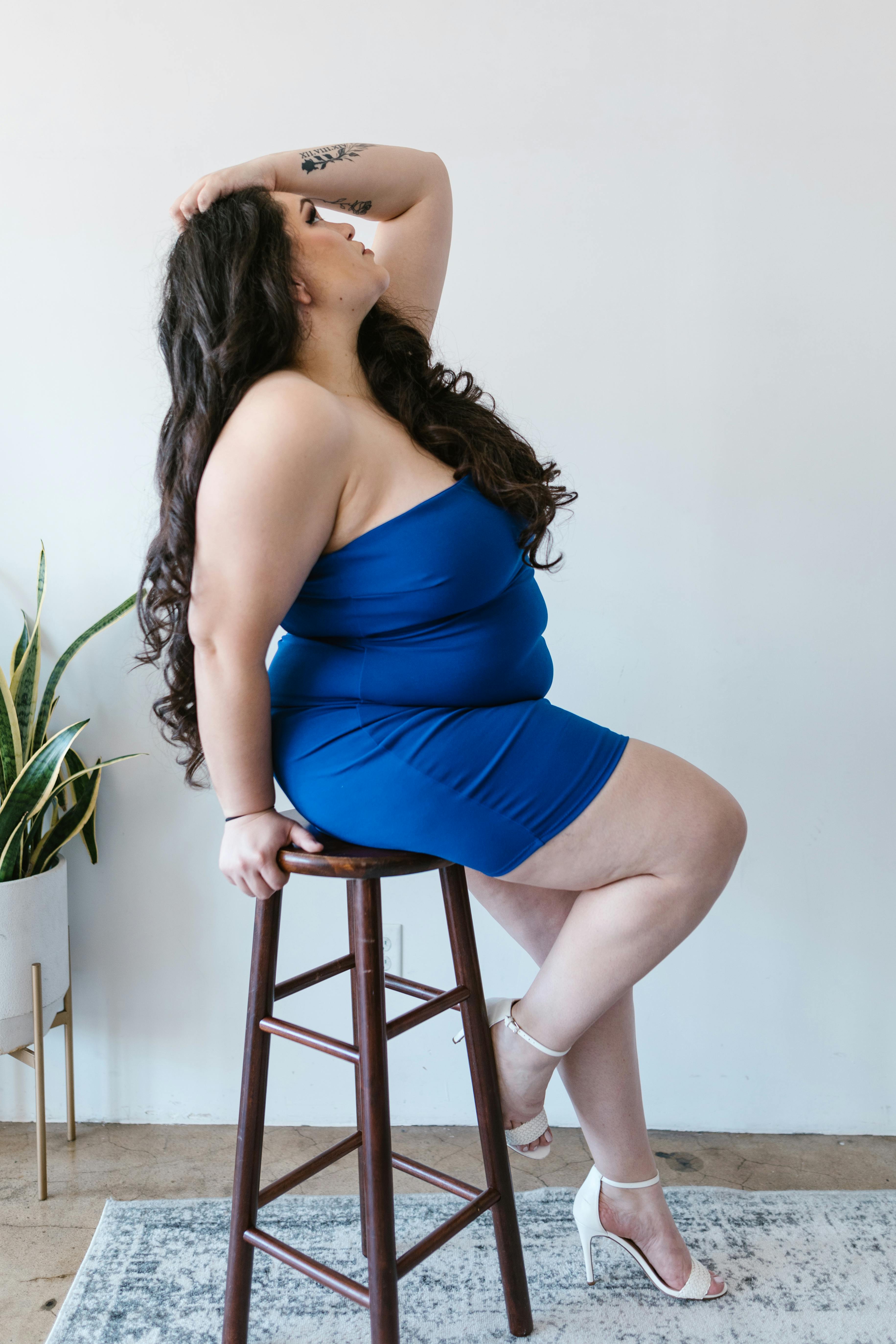 a woman in blue dress sitting on a stool