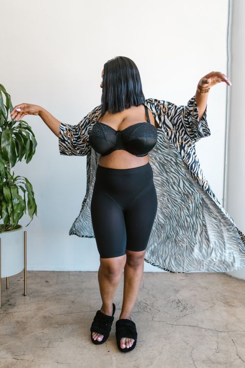 Free Plus-size woman in a stylish robe posing confidently indoors. Stock Photo