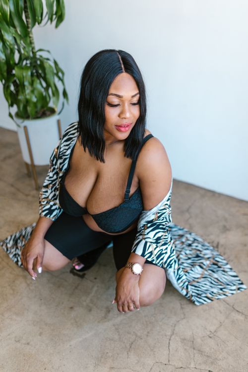 Free Confident plus-size woman poses in a stylish robe and bra indoors on a concrete floor. Stock Photo