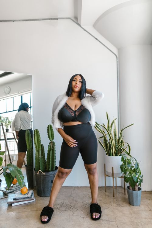 Free Plus size model confidently poses in stylish outfit surrounded by plants indoors. Stock Photo