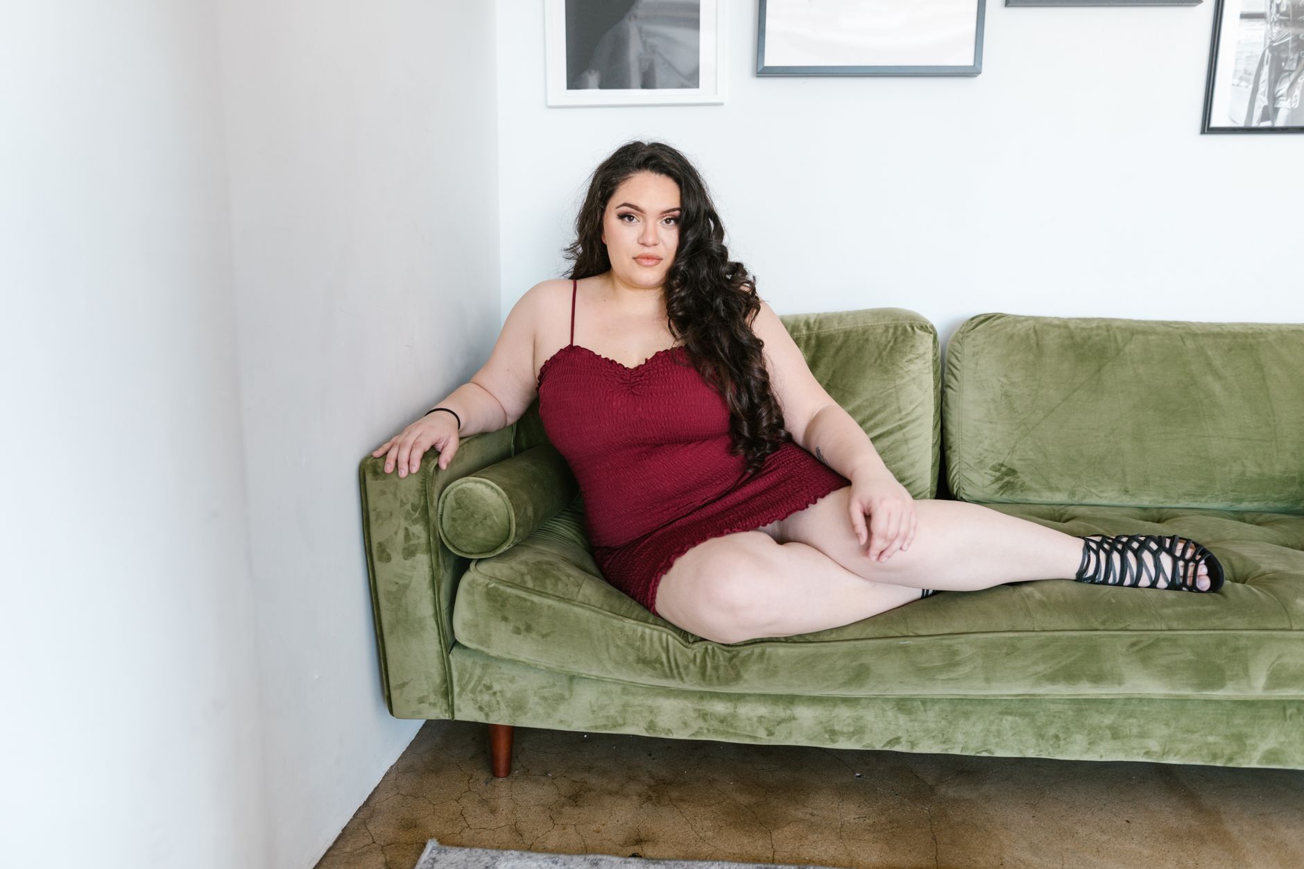 A plus-size woman lounging confidently on a green sofa, showcasing body positivity.