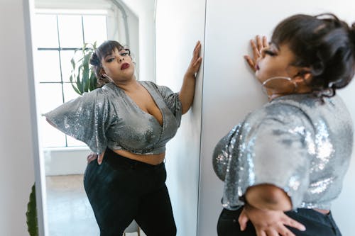 Curvy Woman Standing in Front of a Mirror Stock Photo