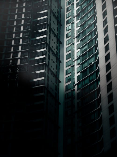 Exterior of contemporary high rise apartment buildings with windows located on street with dark shadow in modern district of city