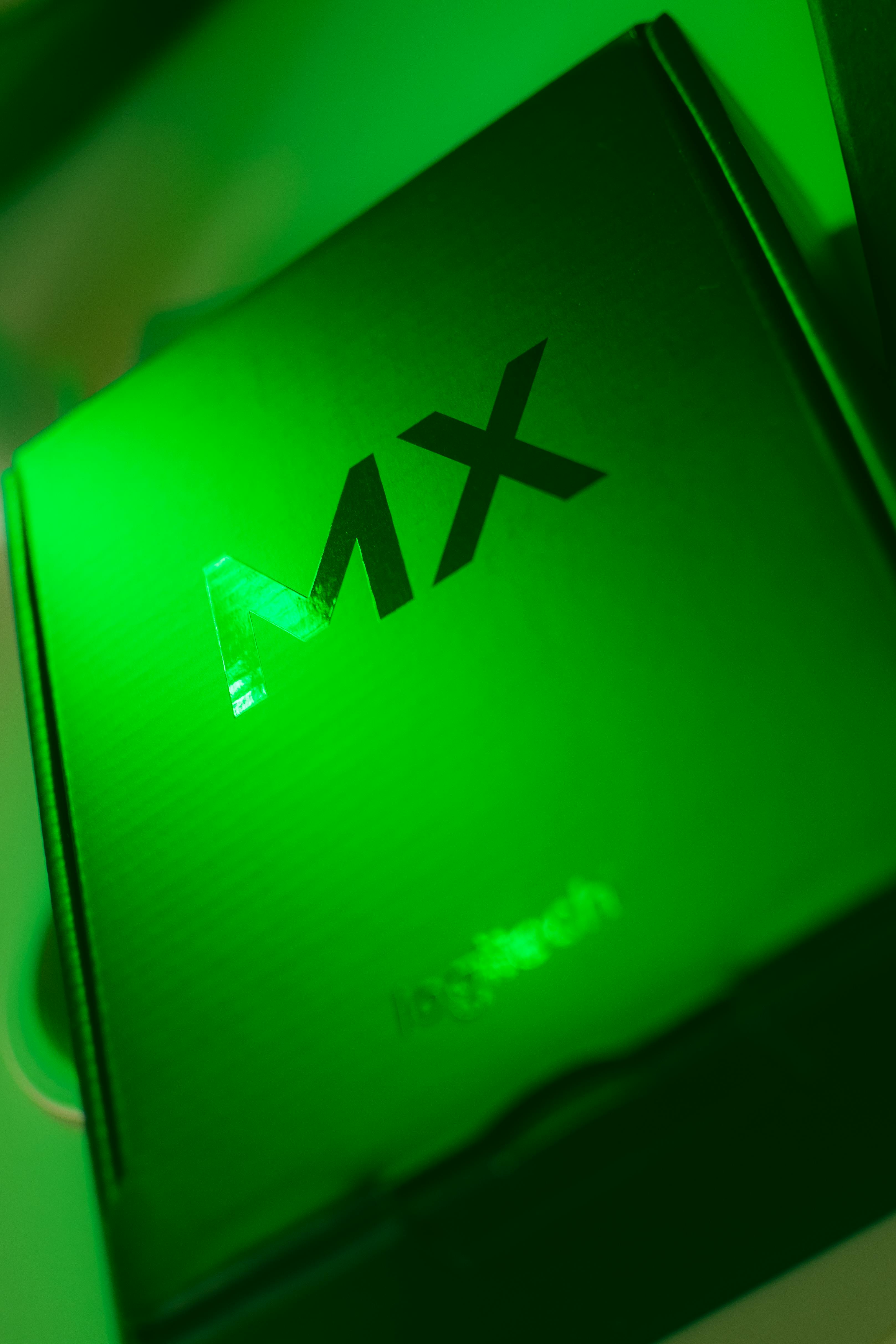 Close-up of a green box with 'MX' text under neon lighting, creating a striking visual.