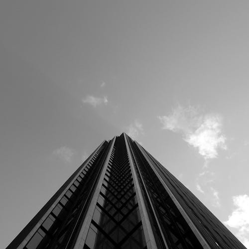 From above of black and white contemporary skyscraper with geometric facade under cloudless sky in sunlight