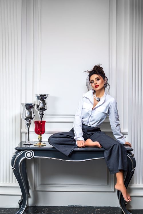Free Elegant woman posing indoors on a table, showcasing fashion style with decorative elements. Stock Photo