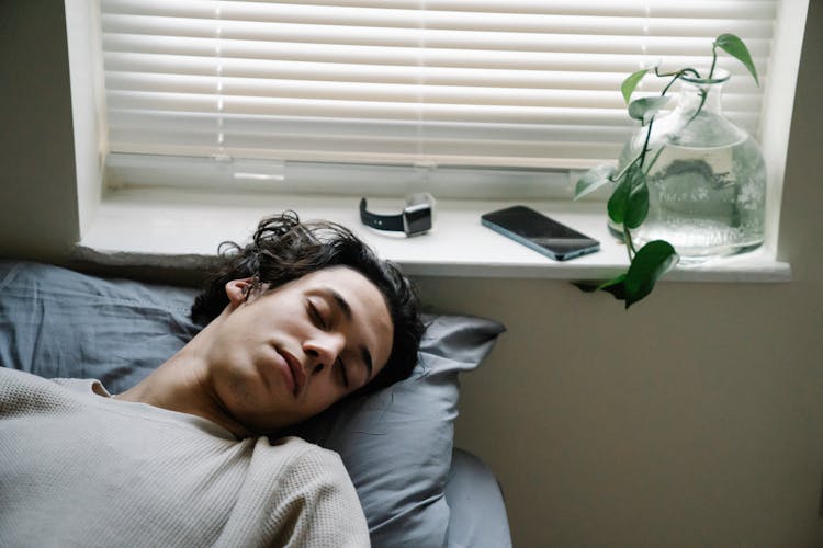 Youngster Sleeping Near Gadgets In Bedroom