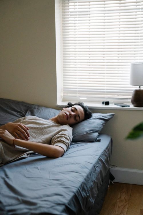 Free Carefree young guy in sleepwear sleeping on bed with gray sheets during day off at home Stock Photo