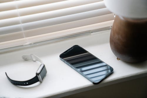 Free Smartphone and wristwatch on windowsill near lamp Stock Photo
