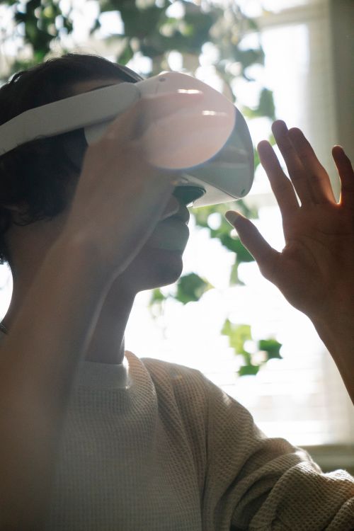 Free A young adult using a VR headset, experiencing immersive virtual reality indoors. Stock Photo