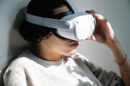 Free A woman immersed in a virtual reality experience with a VR headset indoors. Stock Photo