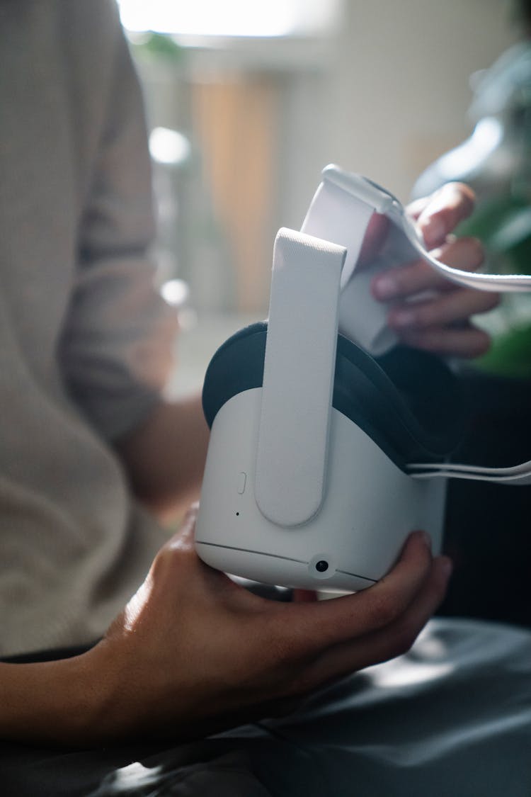 Crop Faceless Man Sitting At Home With VR Goggles In Hands