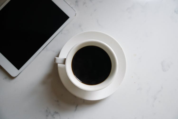 Cup Of Coffee And Tablet Arranged On Marble Table