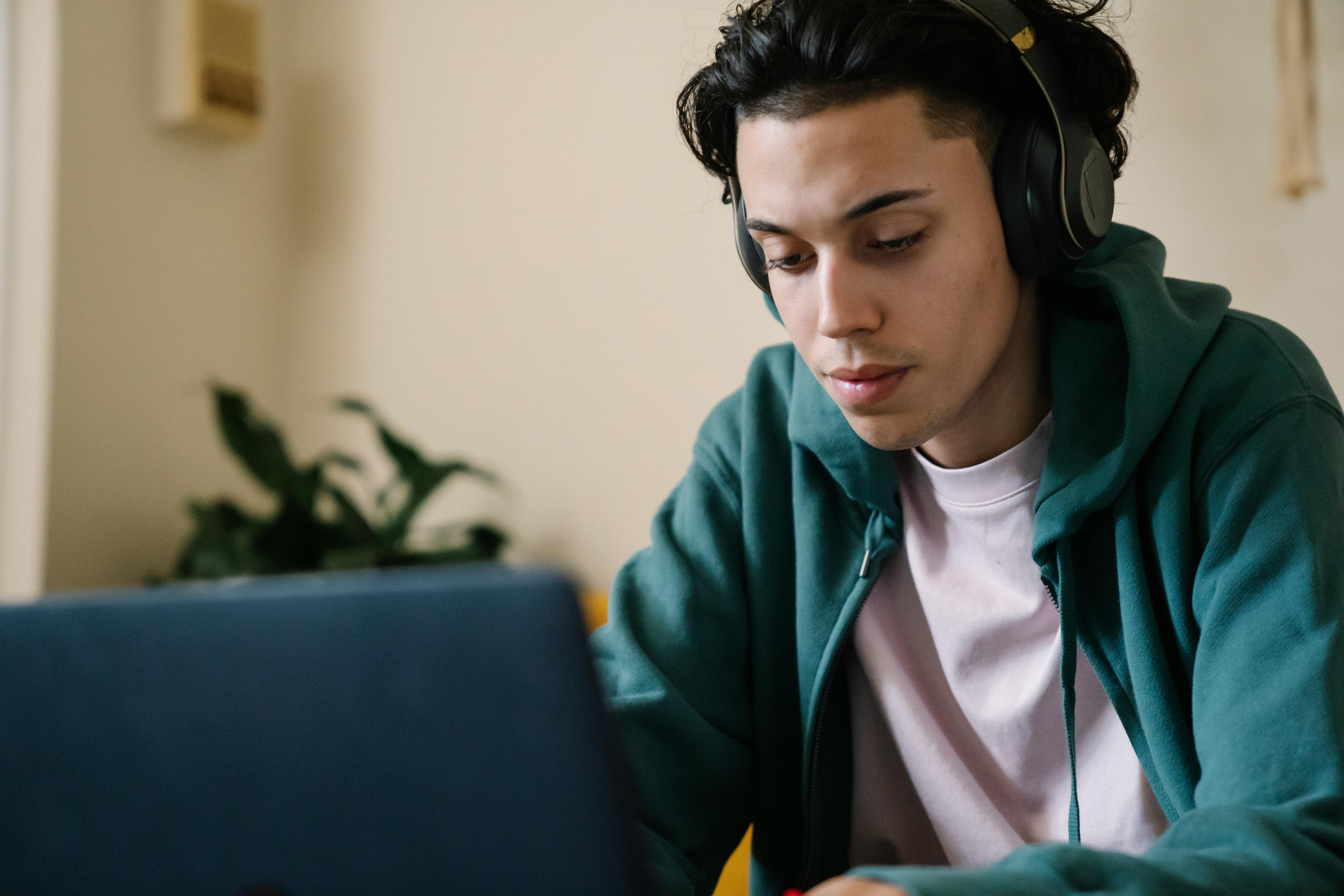 concentrated man in headphones working on laptop at home