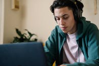 Concentrated man in headphones working on laptop at home