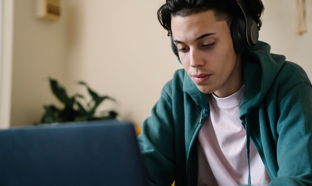 Student with headphones focused on laptop during DET Interactive Speaking task