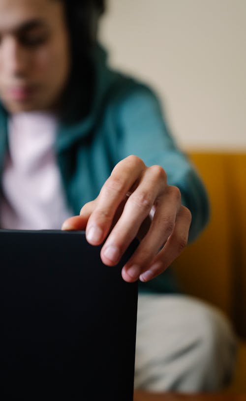 Crop male sitting on sofa and preparing for online work on netbook at home