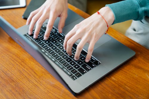Man typing on keyboard while working on laptop
