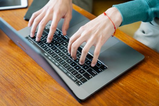 High angle of crop anonymous male freelancer typing on laptop placed on table near devices for remote work