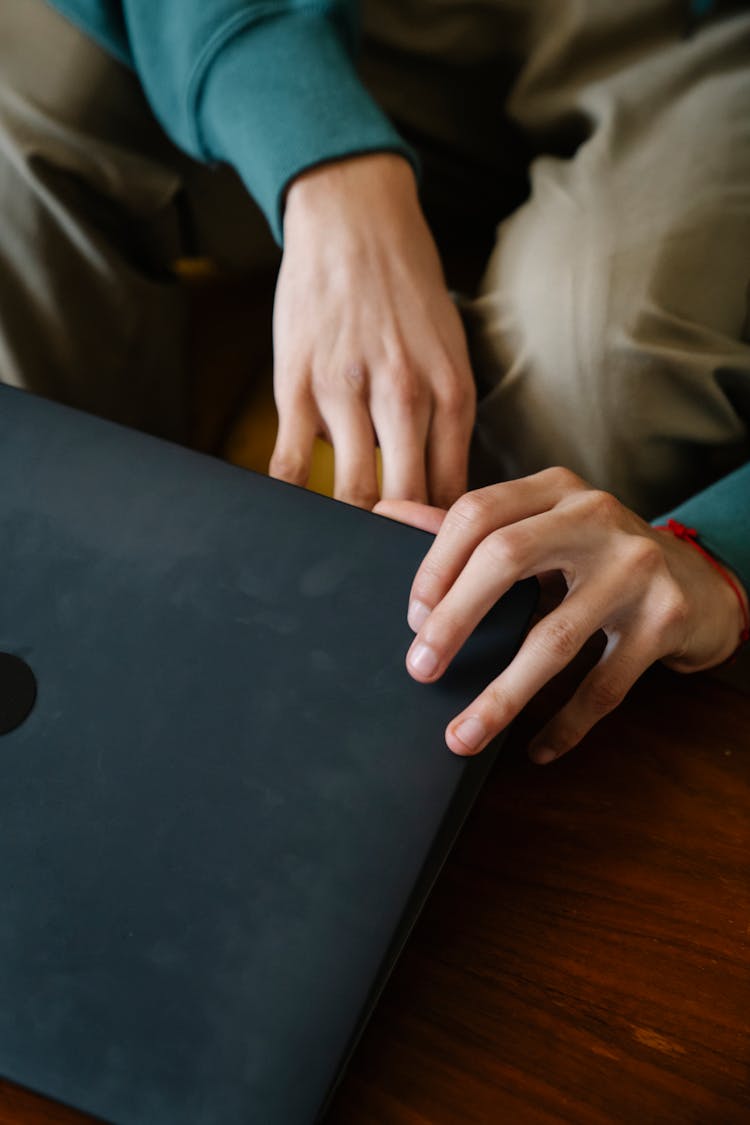 Man Opening Laptop Placed On Table