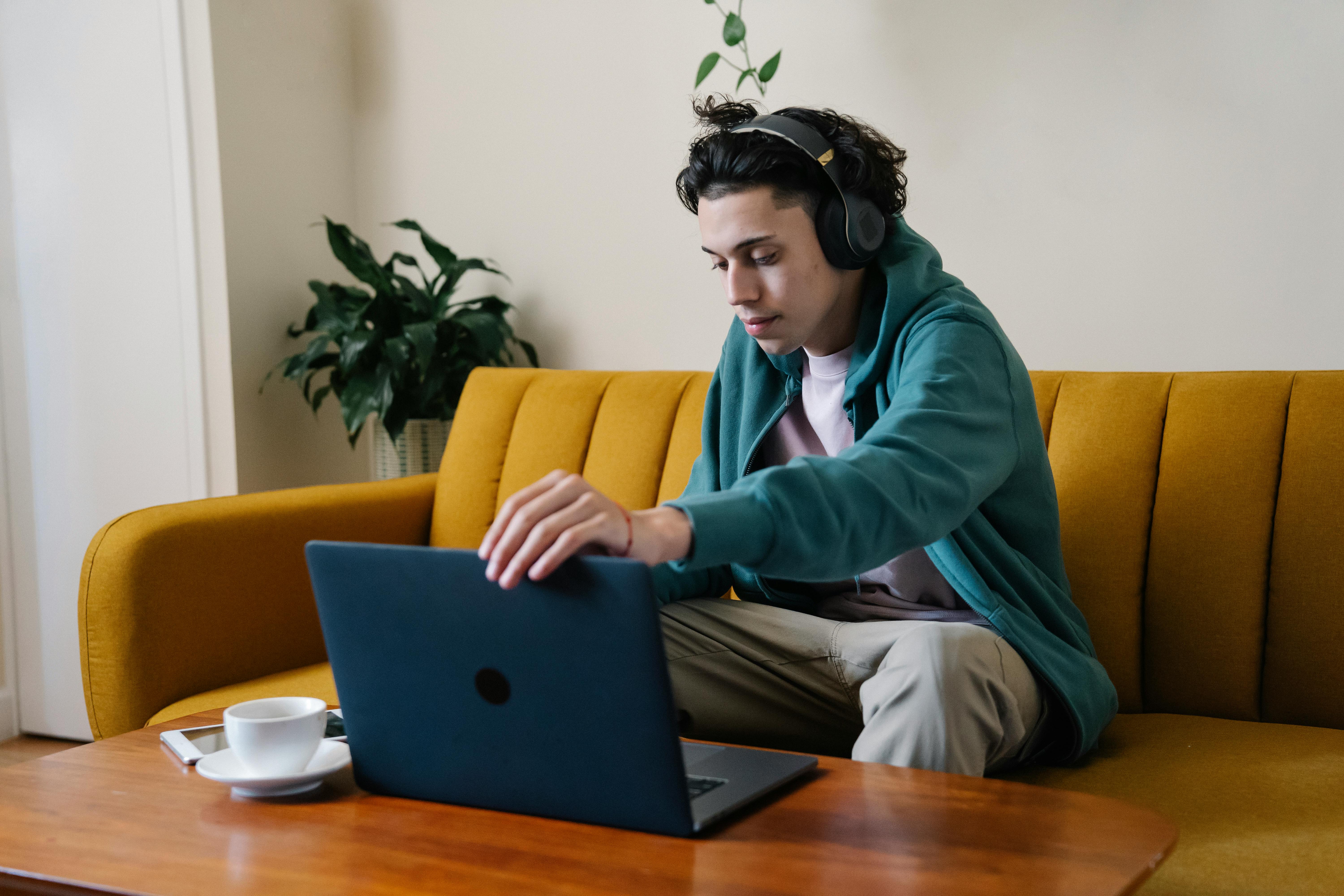 serious man in wireless headphones using laptop