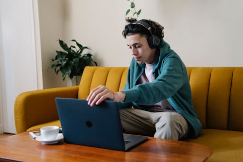 Serious man in wireless headphones using laptop