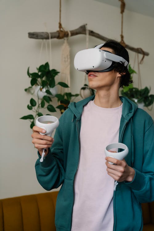 Free Man playing video game in VR headset with remote controllers Stock Photo